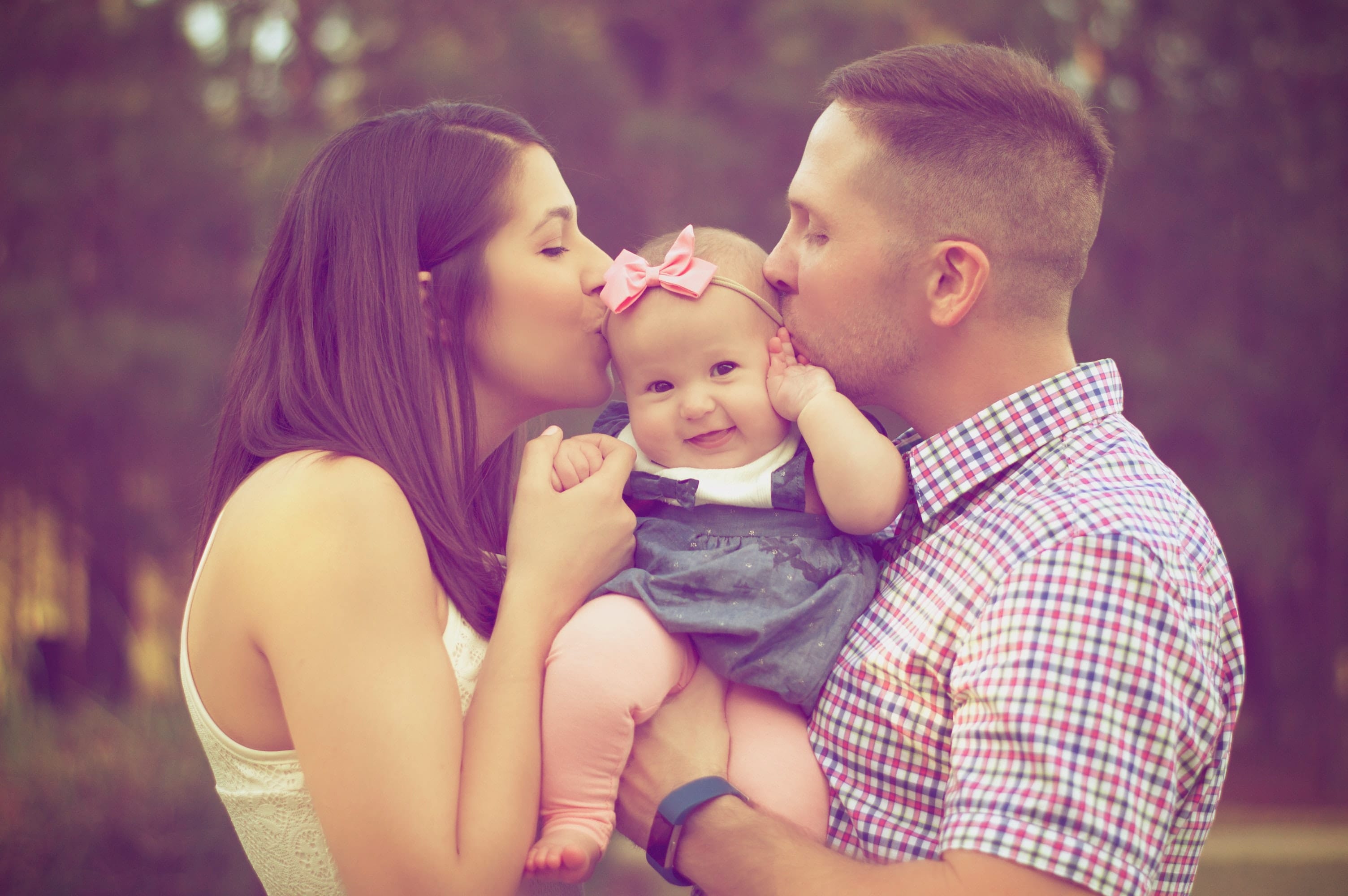 Baby girl gets kisses from parents