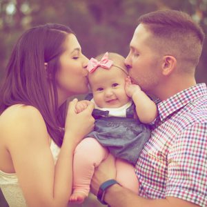 Baby girl gets kisses from parents